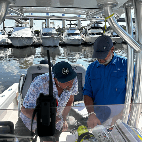 Two men on a boat at marina.