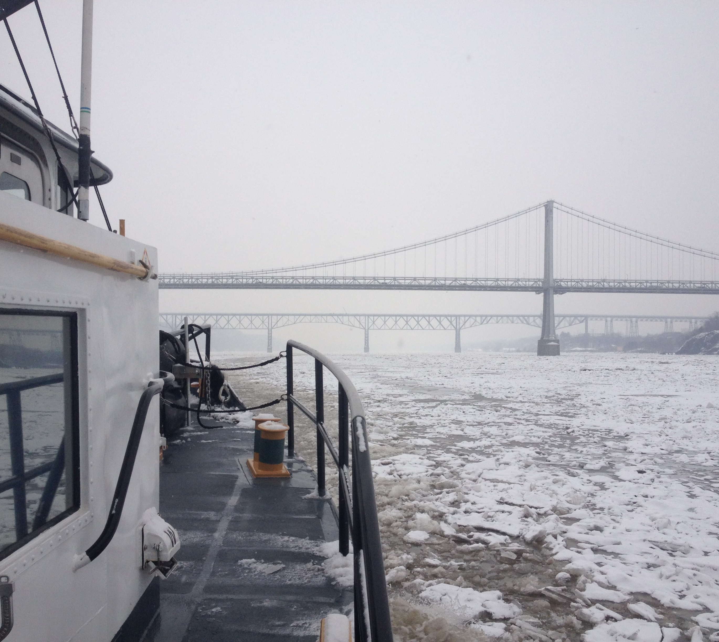 Boat on icy river near bridge