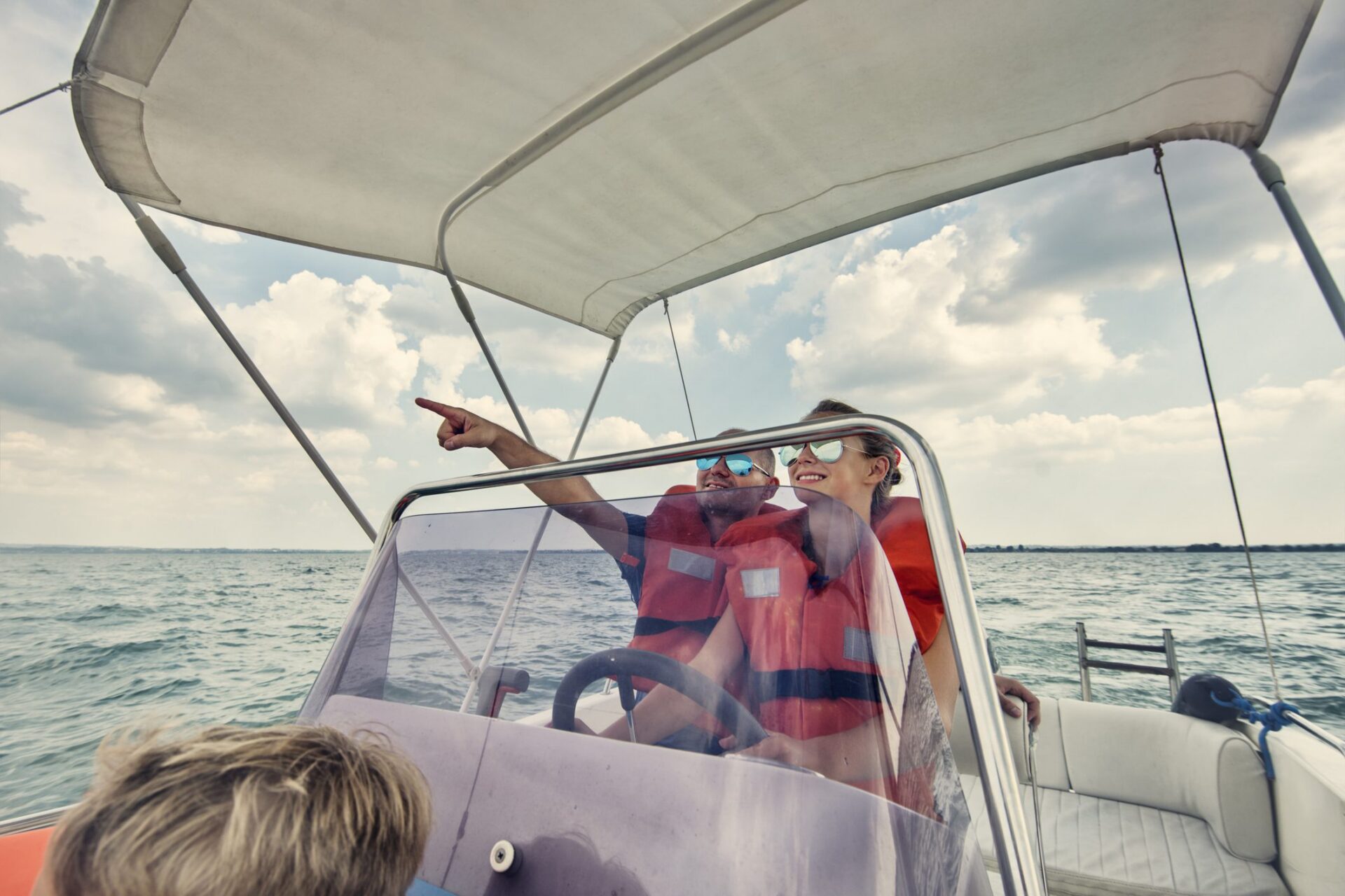Two people steering a boat, pointing ahead.