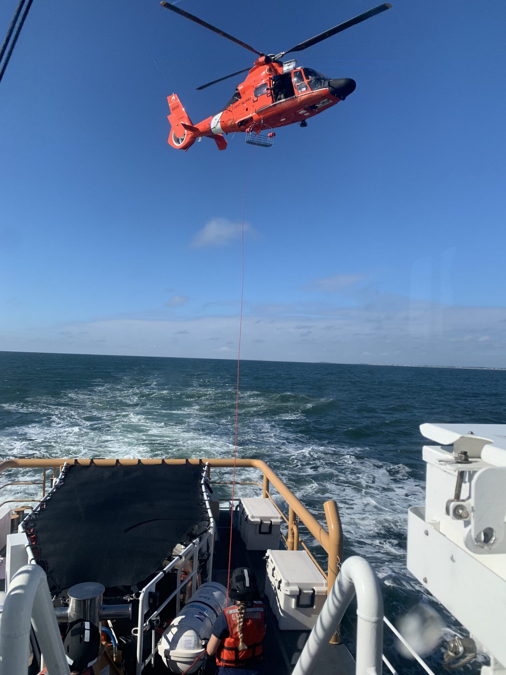 Helicopter hovers above boat at sea.